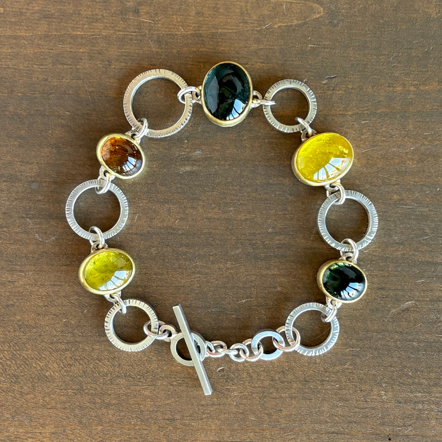Bracelet with circular links and embedded stones on a wooden surface