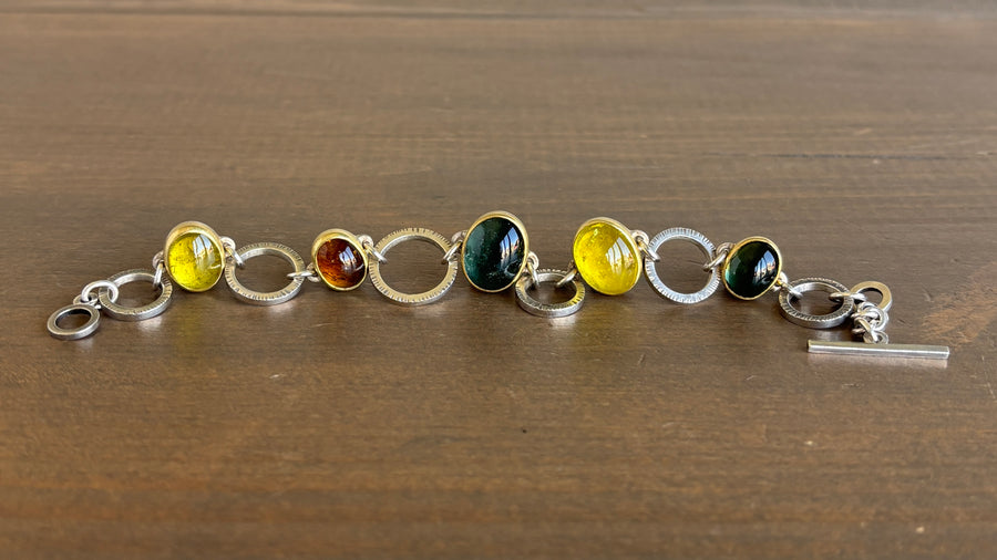 Bracelet with circular links and colored beads on a wooden surface