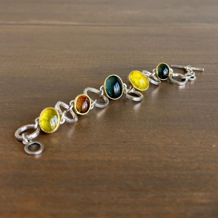 Silver bracelet with colorful gemstones on a wooden surface