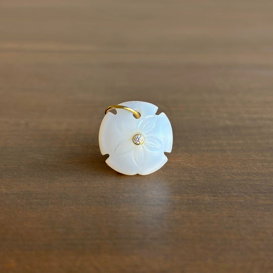 White jade pendant with gold accents on a wooden surface