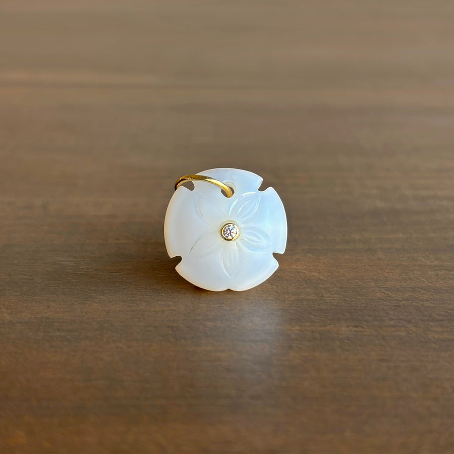 White jade pendant with gold accents on a wooden surface