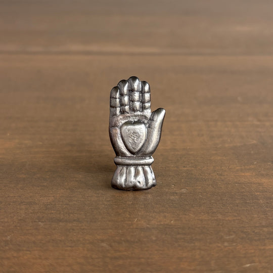 Small silver hand-shaped object on a wooden surface