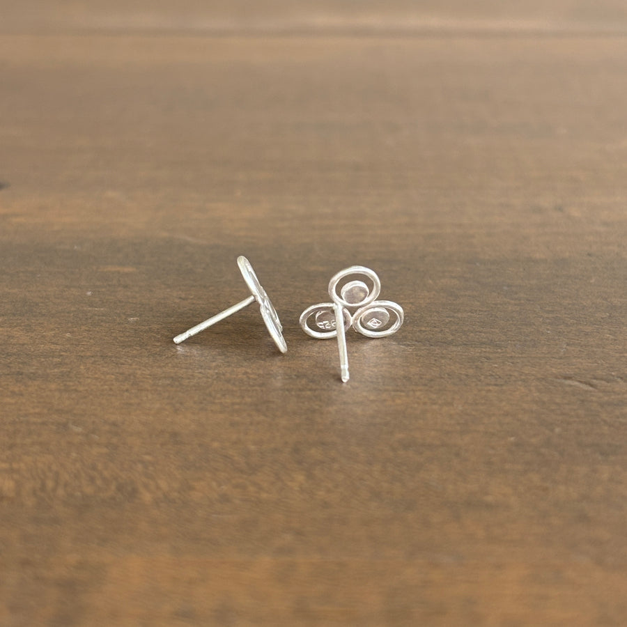 Pair of silver stud earrings on a wooden surface