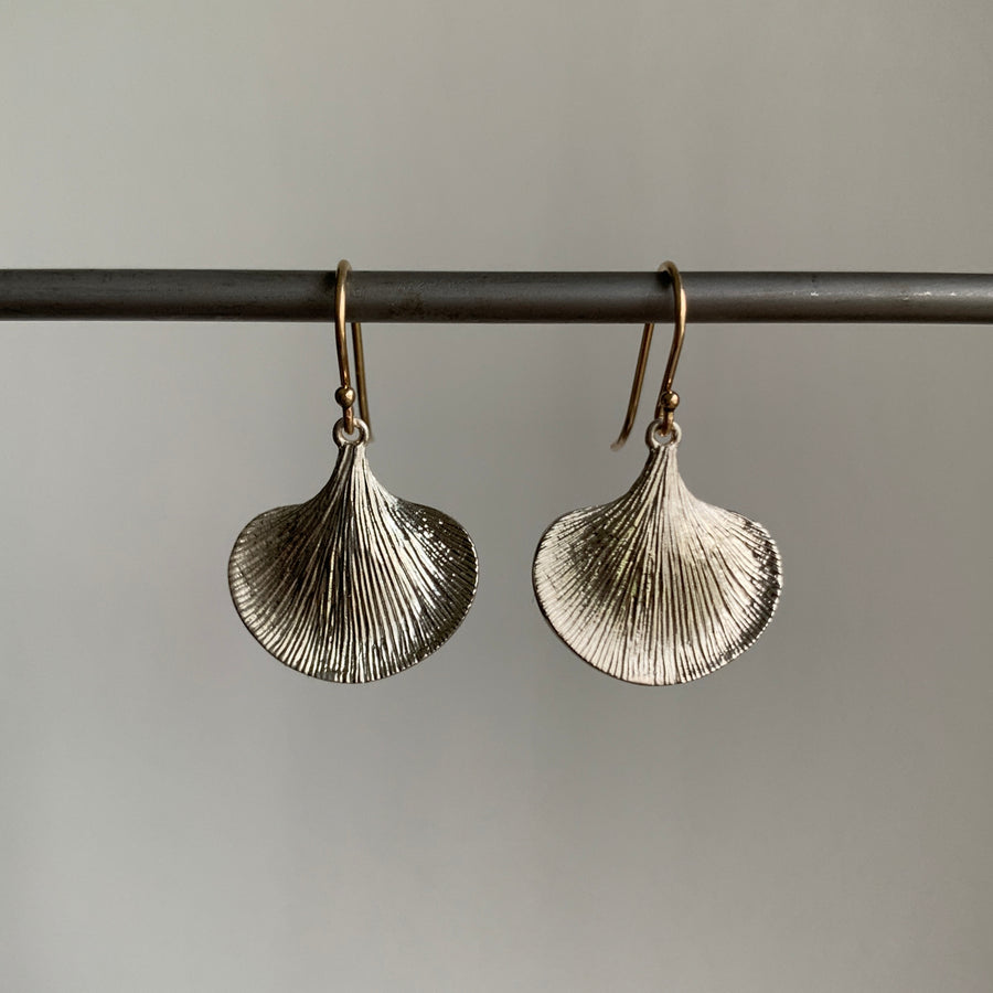 Pair of silver leaf-shaped earrings on a gray background