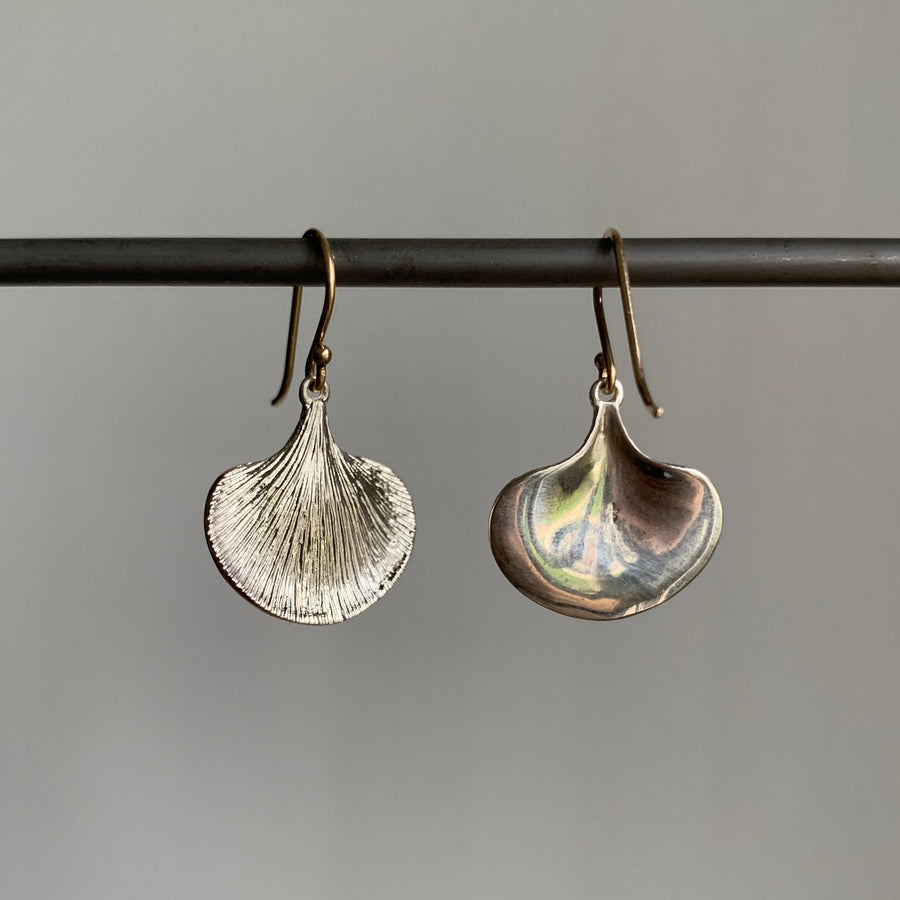 Silver leaf-shaped earrings on a gray background