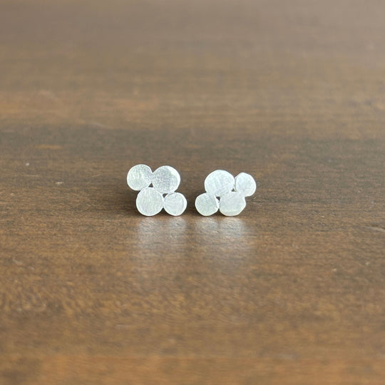 Pair of silver bubble-shaped earrings on a wooden surface