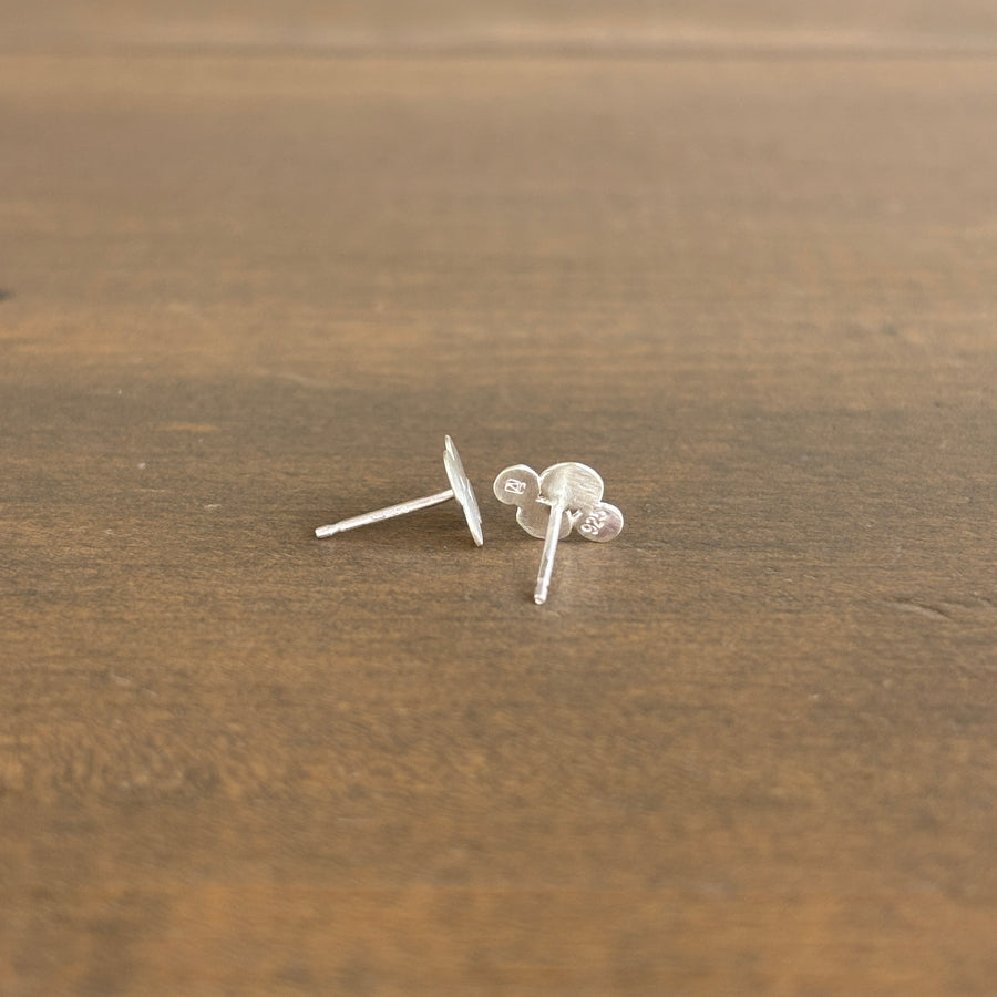 Silver stud earrings on a wooden surface