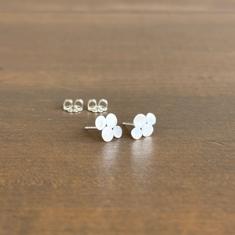 bubble-shaped silver earrings on a wooden surface