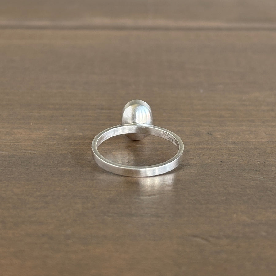 Silver ring with a spherical design on a wooden surface