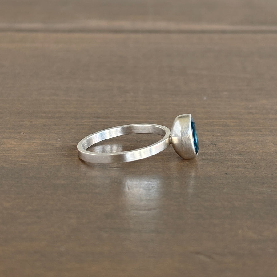 Silver ring with a blue gemstone on a wooden surface