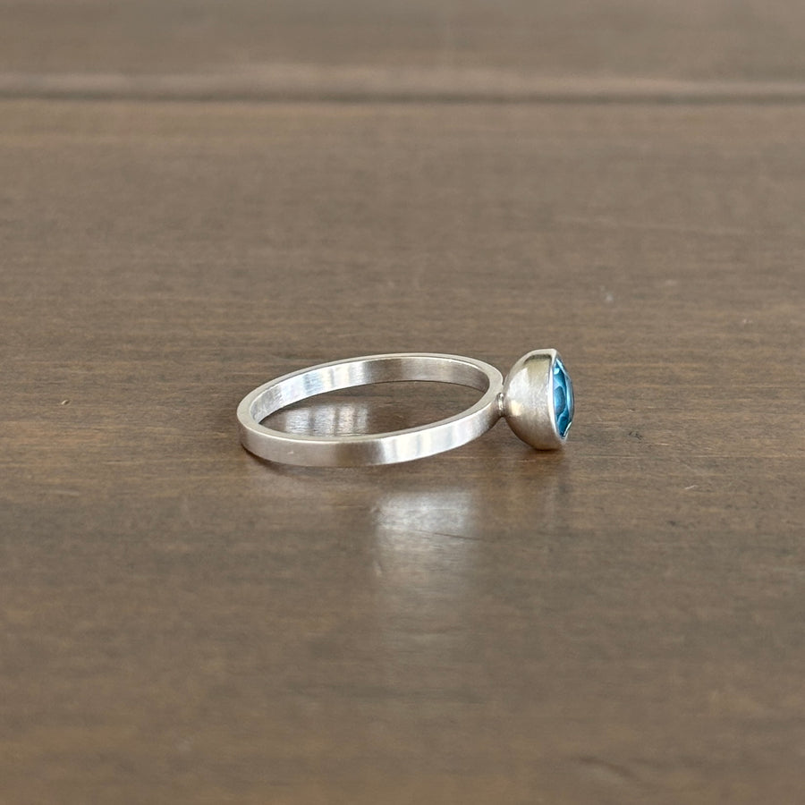 Silver ring with a blue gemstone on a brown surface