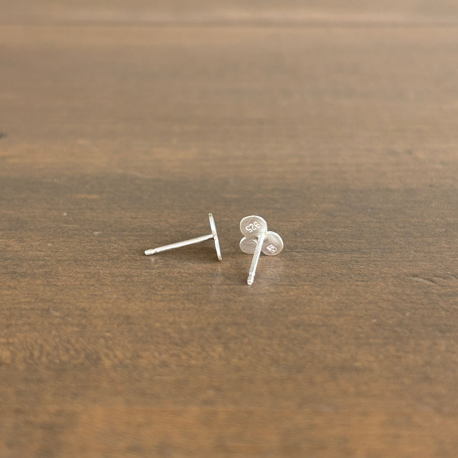 Silver stud earrings on a wooden surface