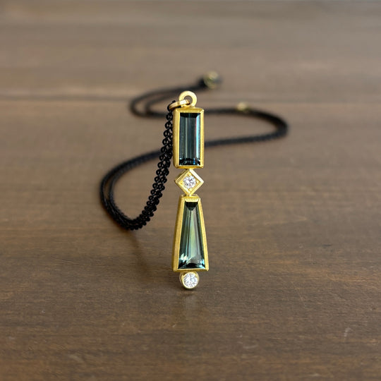 Gold necklace with green gemstone pendant on a wooden surface