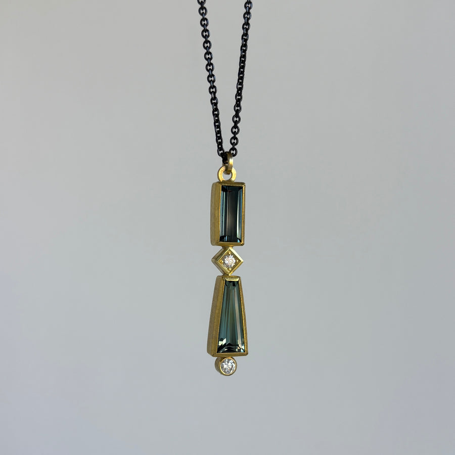 Gold and green pendant necklace on a gray background