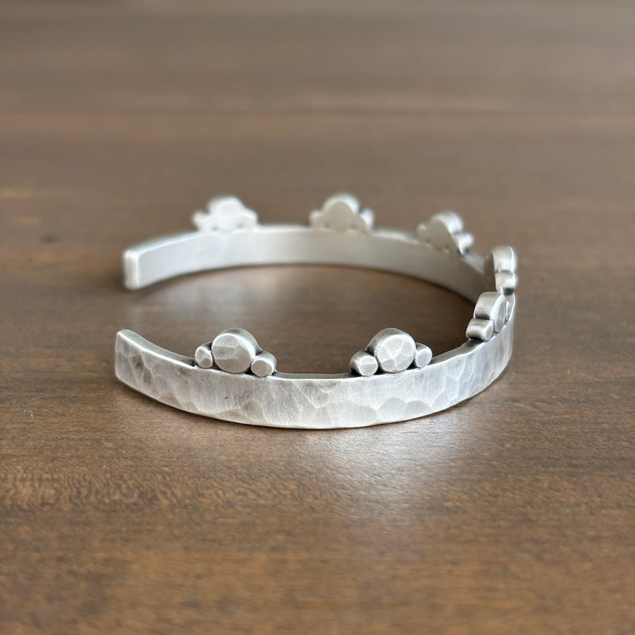 Silver bracelet with textured design on a wooden surface