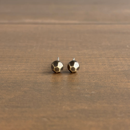 Pair of geometric gold stud earrings on a wooden surface