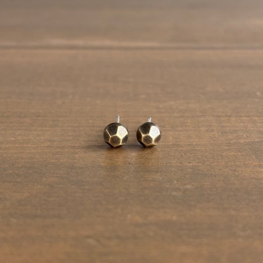 Pair of geometric gold stud earrings on a wooden surface