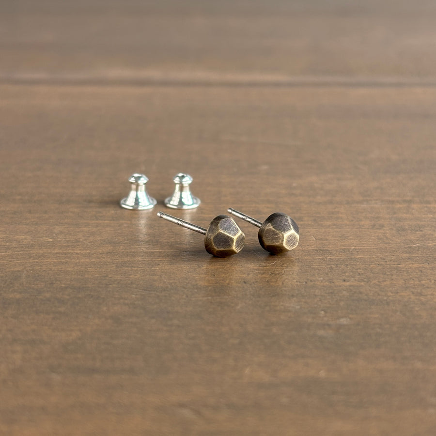 Pair of geometric gold stud earrings on a wooden surface