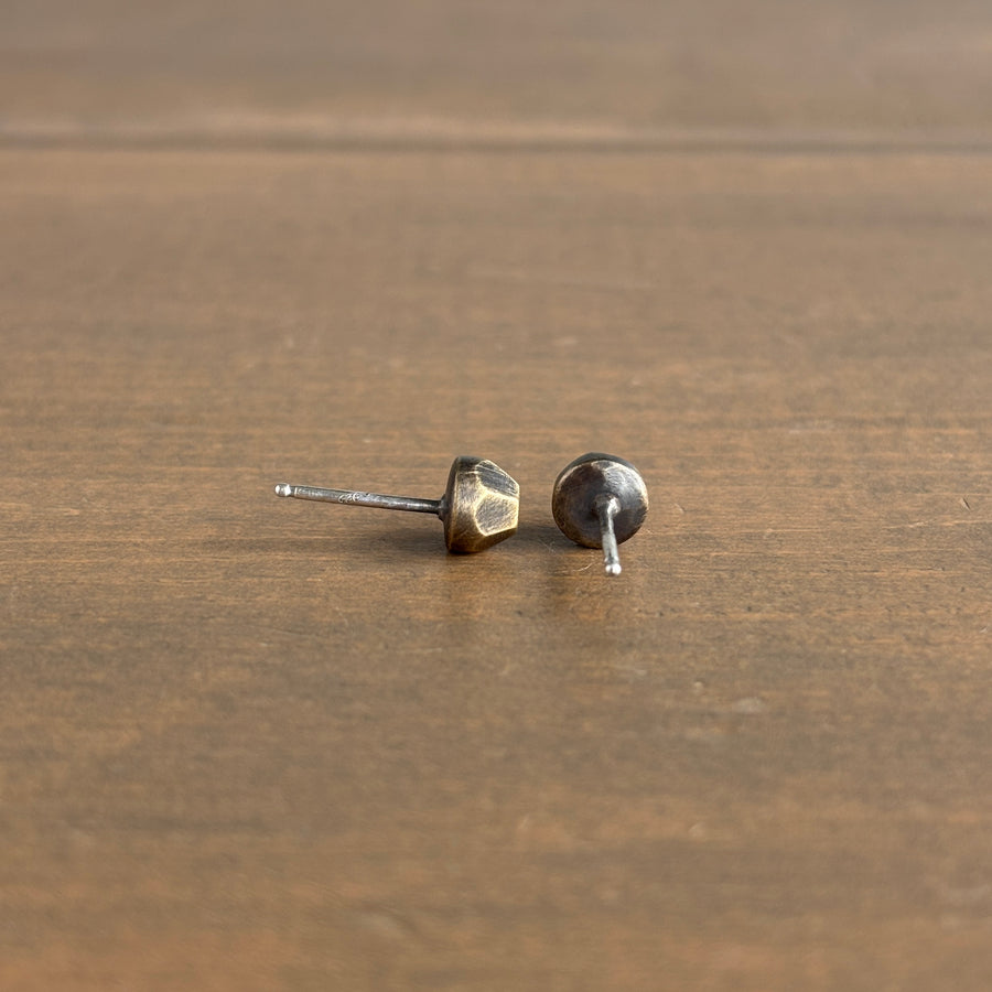 Pair of bronze-colored earrings on a wooden surface