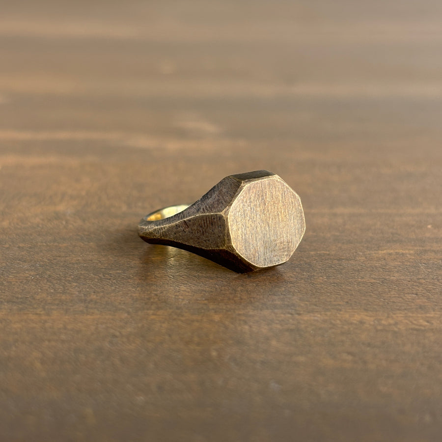 Bronze ring with a geometric design on a wooden surface