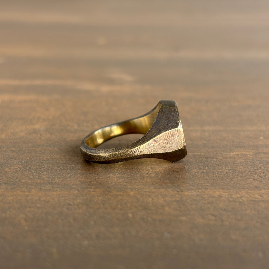 Gold ring with a textured design on a wooden surface