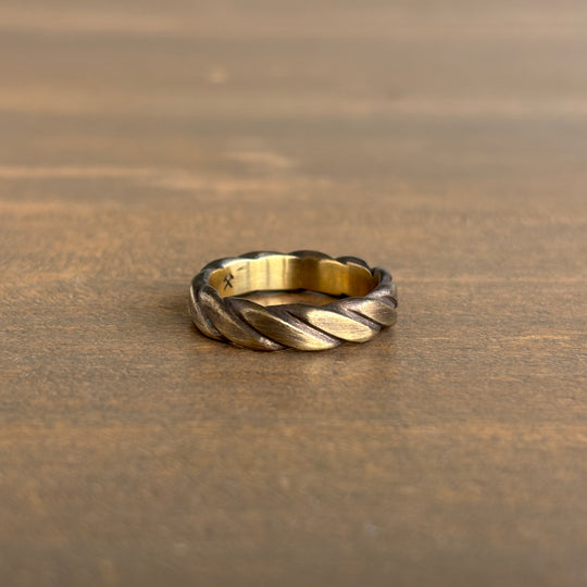 brass braided ring on a wooden surface