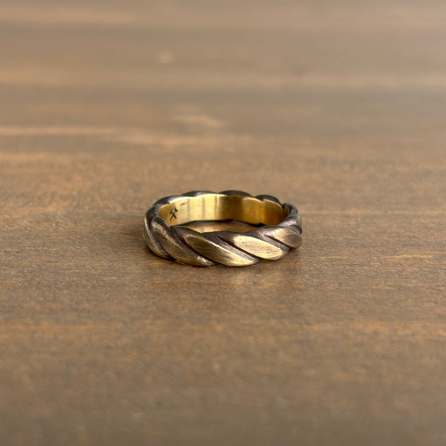 brass braided ring on a wooden surface
