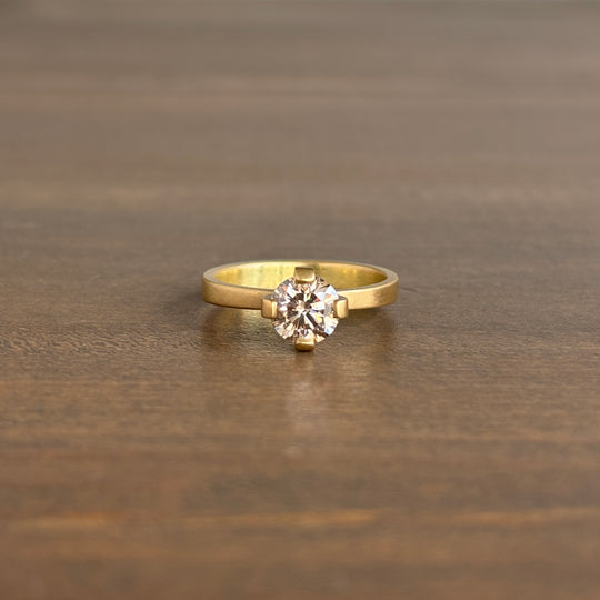 Gold ring with a diamond on a wooden surface lola brooks