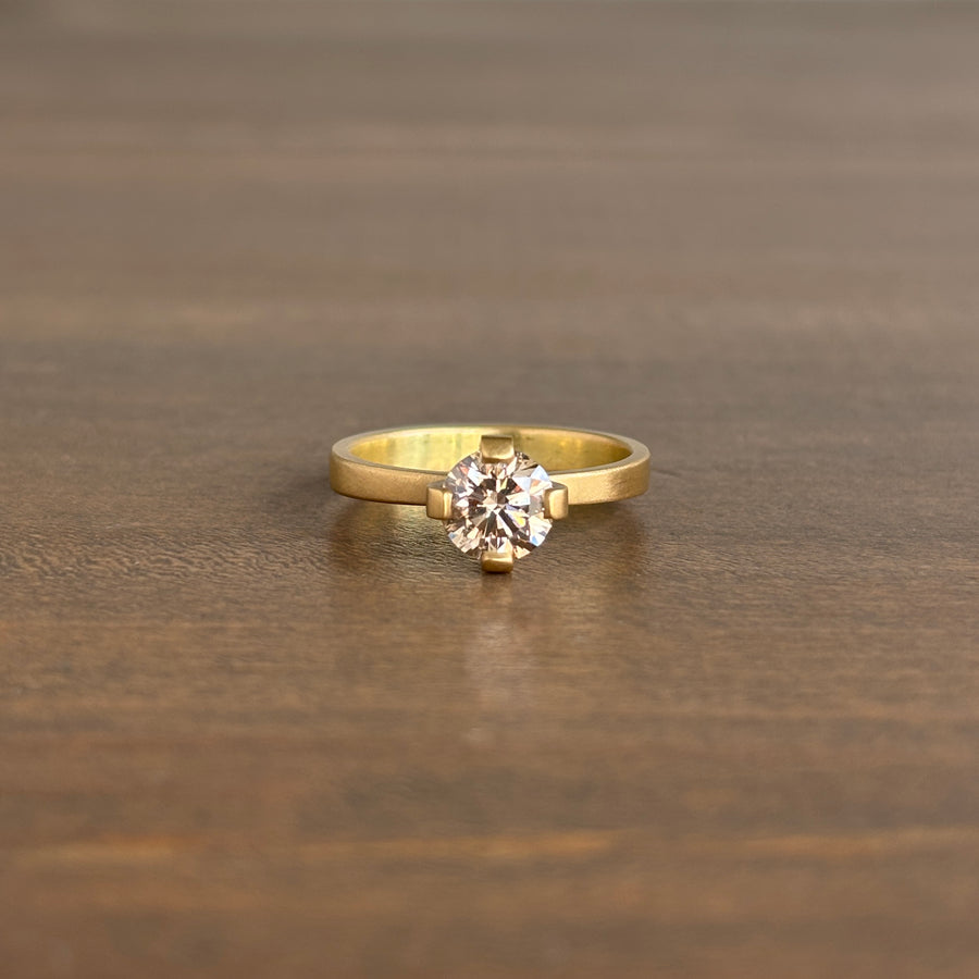 Gold ring with a diamond on a wooden surface lola brooks