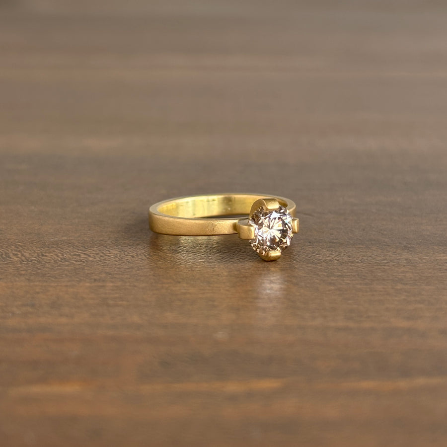 Gold ring with a diamond on a wooden surface